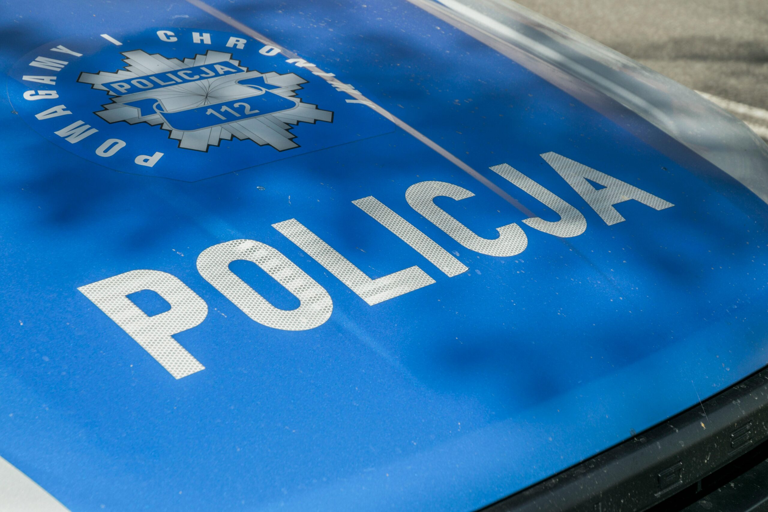 Detailed image of a Polish police car hood showing insignia and text 'Policja'.